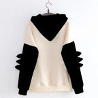 Back view of kawaii dinosaur sweatshirt in cream with black hood and dinosaur spikes on sleeves