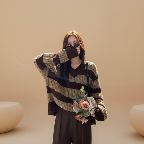 Woman wearing plus size casual spring sweater with brown and beige stripes holding a bouquet outdoors