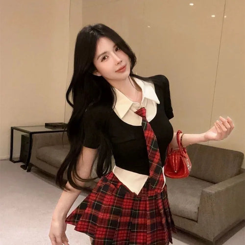 Woman wearing a preppy style two piece skirt set with black top and red plaid skirt indoors