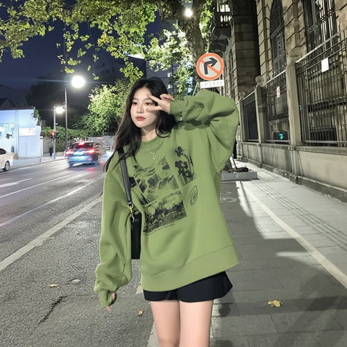 Young woman wearing a cute green harajuku design hoodie posing on a city sidewalk at night