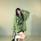 Young woman wearing cute green harajuku design hoodie posing on city street at night