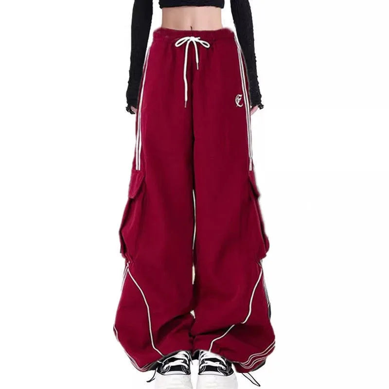 Red wide-leg pants from three piece streetwear set for women with white drawstring and black sneakers