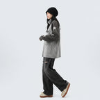 Woman wearing a double zipper autumn jacket for women with star patterns on sleeves paired with striped pants and beige shoes