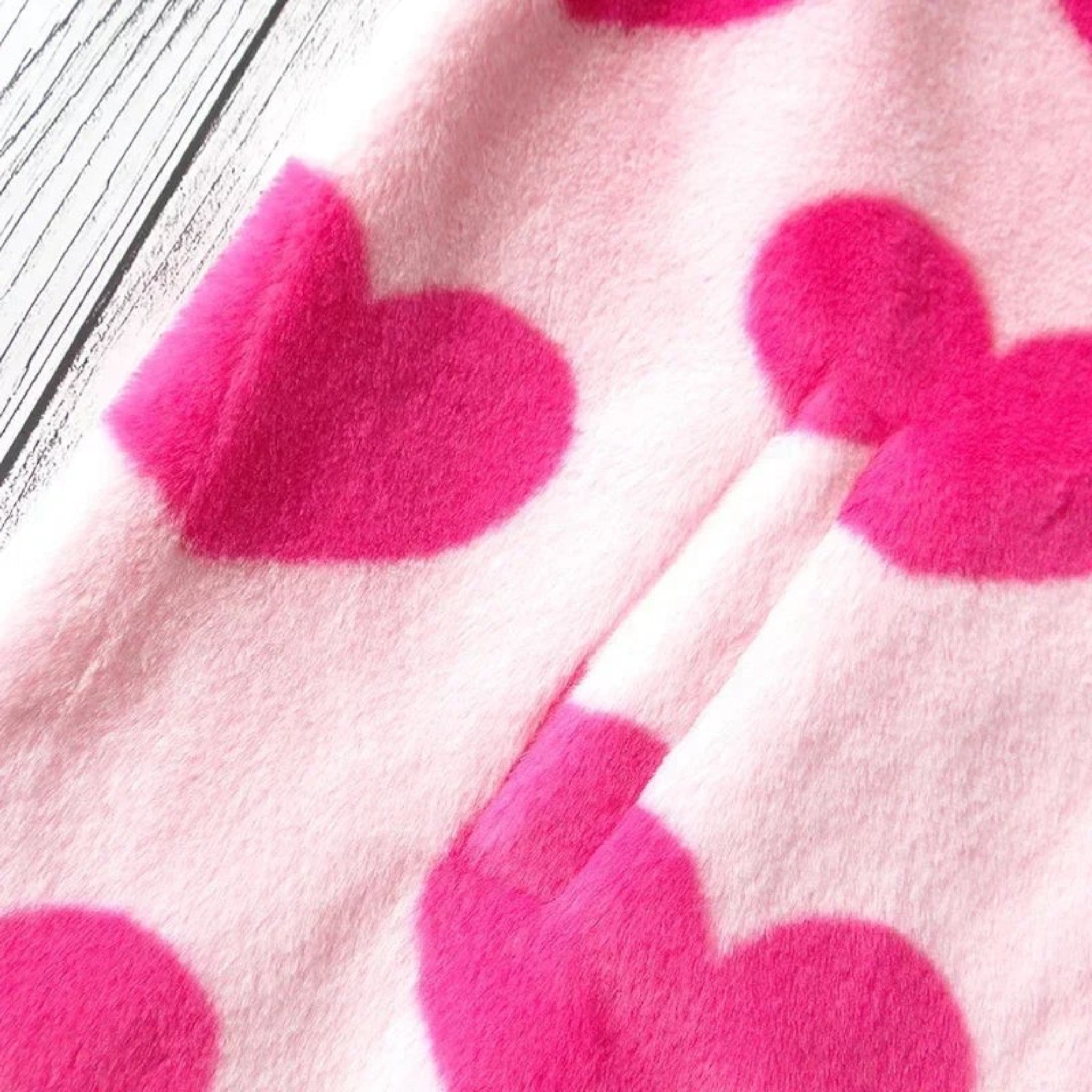 Close-up of pink harajuku heart print plush jacket with vibrant red hearts and soft fuzzy texture