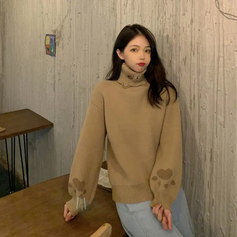 Woman wearing a beige japanese cartoon cat pullover for women with paw prints on sleeves sitting indoors