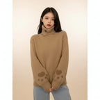 Woman wearing a brown japanese cartoon cat pullover for women with paw prints on sleeves indoors