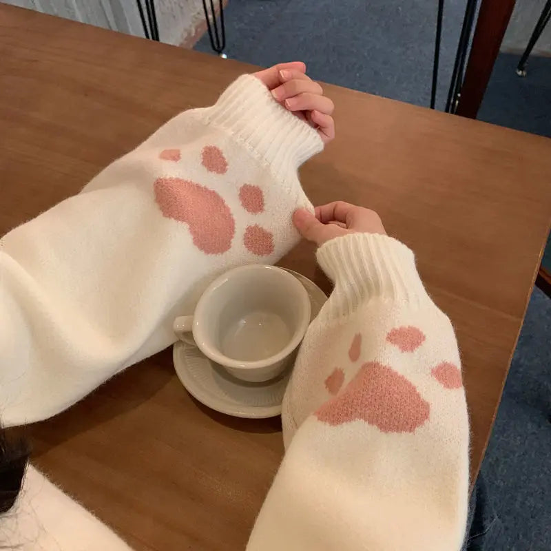 White japanese cartoon cat pullover for women with pink paw prints on sleeves and ribbed cuffs