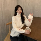 Woman wearing a white japanese cartoon cat pullover for women with paw prints on sleeves sitting at a table