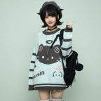 Woman wearing a kawaii cat sweater for women in light blue with black cat design and striped sleeves