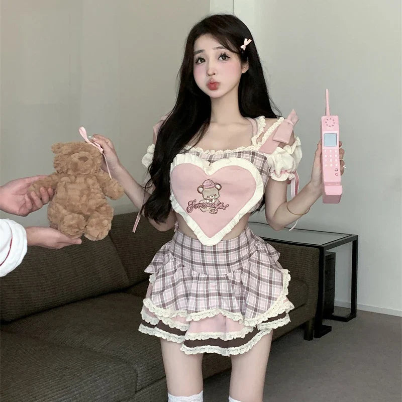 Young woman wearing kawaii lolita skirt set in pastel pink and plaid holding teddy bear and pink toy phone