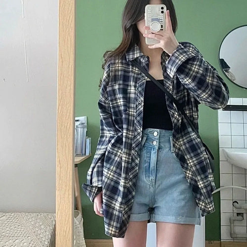 Woman wearing plaid shirt black dress set for women with blue denim shorts taking mirror selfie