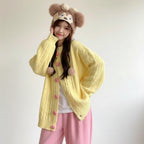 Yellow embroidered cardigan for women with pink buttons and pom pom details worn with pink pants