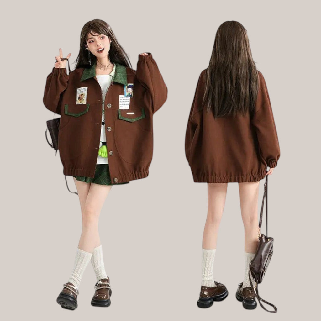 Vusy Kawaii Shop Official brown bomber jacket with green collar and pockets, featuring Japanese style patches. Model wears it with a white top and green plaid skirt.