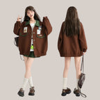 Vusy Kawaii Shop Official brown bomber jacket with green collar and pockets, featuring Japanese style patches. Model wears it with a white top and green plaid skirt.