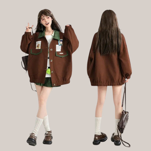 Vusy Kawaii Shop Official brown bomber jacket with green collar and pockets, featuring Japanese style patches. Model wears it with a white top and green plaid skirt.