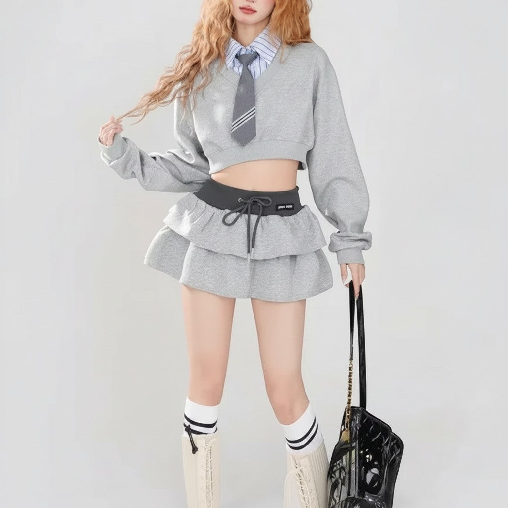 Vusy Kawaii Shop Official grey two-piece set with cropped sweatshirt and tiered ruffle skirt, styled with a blue striped shirt and grey tie.