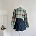 Back view of women's ethnic sleeveless summer dress styled with a plaid cropped jacket and black skirt