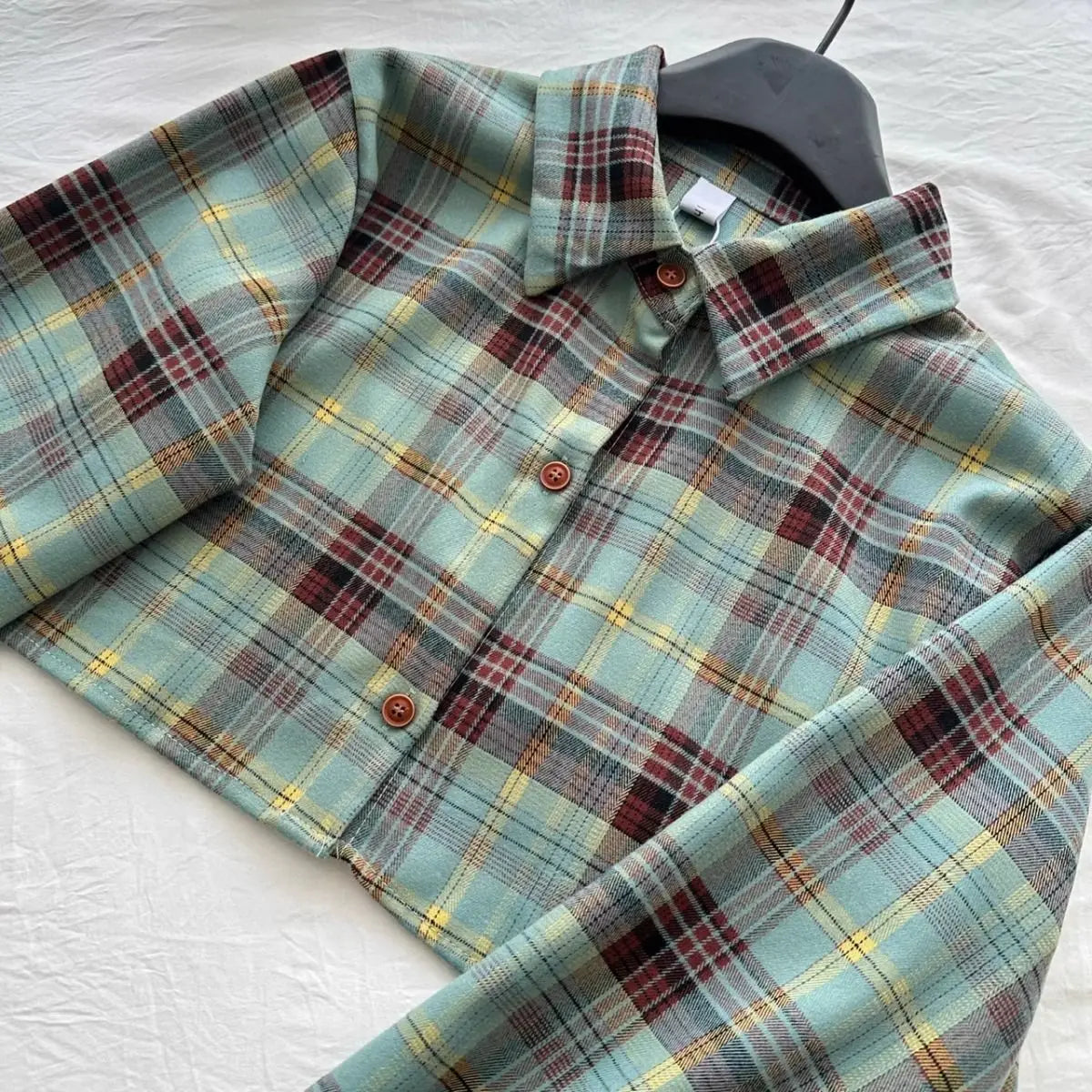 Plaid button-up shirt with green, yellow, and red pattern on black hanger from Vusy Kawai Shop