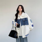 Women wearing women's retro denim baseball jacket with patch details and blue accents holding black handbag
