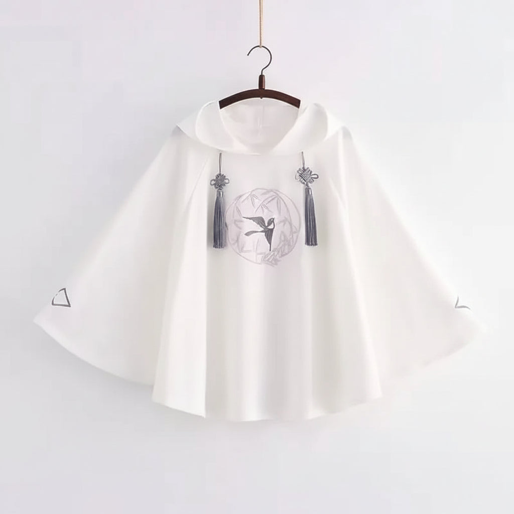 White women's spring autumn cute sweatshirt with wide sleeves and decorative tassels hanging on a wooden hanger
