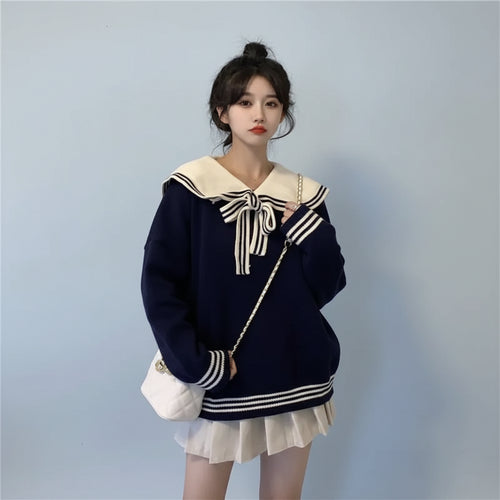 Woman wearing new trendy korean sweaters navy blue with white sailor collar and bow in a bedroom setting