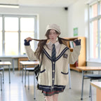 Woman wearing oversized knit cute sweater coat for women in white with navy trim and a schoolgirl outfit